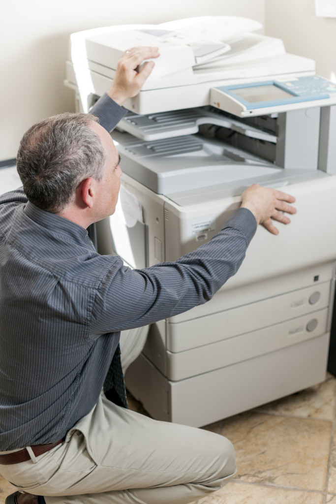 Man opening photocopier in office